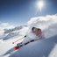 Skier carving through fresh powder snow in sunny mountain landscape